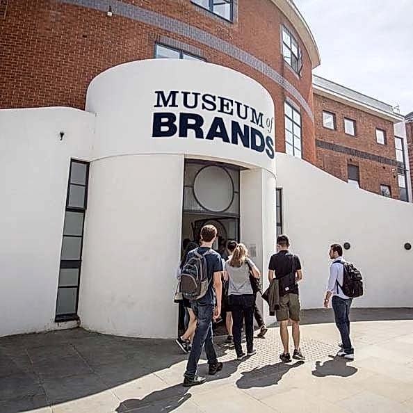 A group of people walk into The Museum of Brands, a white building with Museum of Brands written on the front.